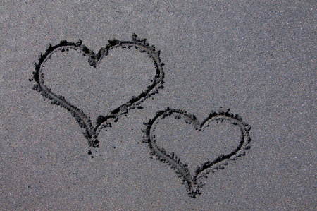 Two heart shapes drawn on a black sand beach in Canggu, Bali - Indonesia