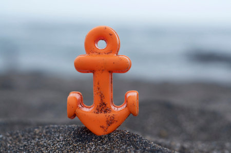 Close up picture of a small orange anchor beach toy placed on the black sand at the Batu Bolong...