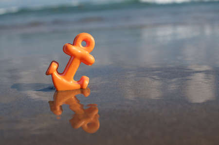 Close up picture of a small orange anchor beach toy placed in the shallow water at the Batu Bolong beach in Canggu, Baliの写真素材