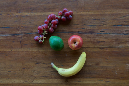 A smiling face made out of different fruits on a wooden tableの写真素材