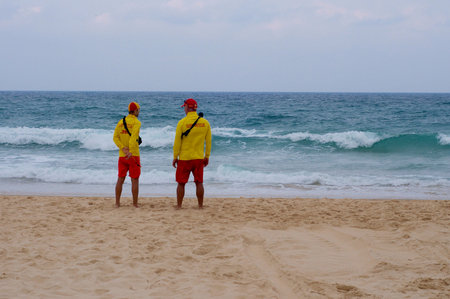 Rear view of two Australian lifeguards (surf rescuers) at Sunfers Paradise Beach
