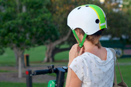 Brisbane, Queensland, Australia - 28th January 2020 : Close up of a woman lacing a helmet for riding an E-scooter in the city of Brisbane. E-scooters are a very good way to travel around a cityのeditorial素材