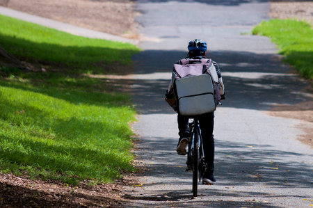 Rear view of an Uber Eats courier on a bicycle in Brisbane. Uber Eats is an American online food...