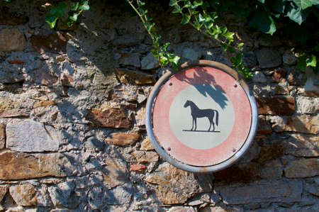 No horse or no horse riding allowed sign hanging in front of a stone wall in Montagnola, Switzerlandの写真素材