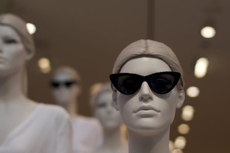 Close up of a cool female mannequin with sunglasses and with others mannequin in background. This...