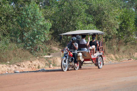 Sihanoukville, Cambodia - 30th December 2018 : Typical Cambodian Tuk Tuk with chinese passengers on board on a sandy road in Sihanoukville, Cambodiaのeditorial素材