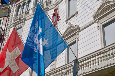 Close up of the flags of city Locarno and Switzerland hanging in front of the Municipio di Locarno building. The building is also called Palazzo Marcacciのeditorial素材