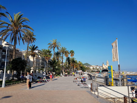 Sitges, Spain - September 20, 2018: Sitges promenade scene on a sunny clear summer day with palm...
