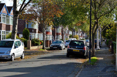 Manchester, England, United Kingdom - 10/22/2018: Autumn urban street with houses and trees lining the road and autumnal leaves on the ground.のeditorial素材