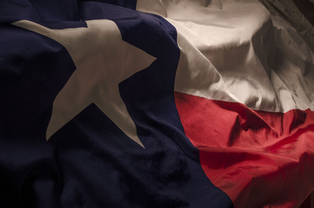 close up view of the Texas Lone Star flag isolating the three separate colors and the single star amongst shadow, high lights and wavesの写真素材