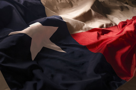close up view of the Texas Lone Star flag isolating the three separate colors and the single star amongst shadow, high lights and wavesの写真素材