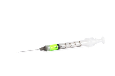 syringe laying on white background with green medicineの写真素材