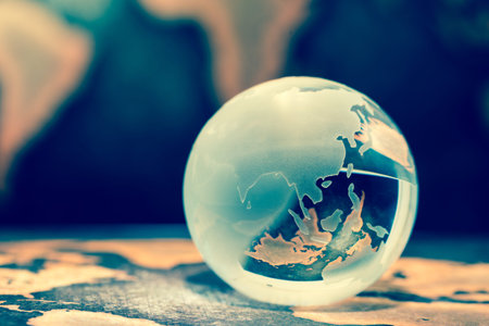 Crystal globe on books against grunge world mapの写真素材