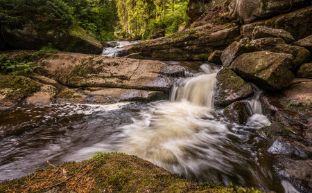 Amazing waterfall hidden deep in Jizera mountains, Czech Republic. Calm and peaceful place with water flowing in cascade river.の写真素材