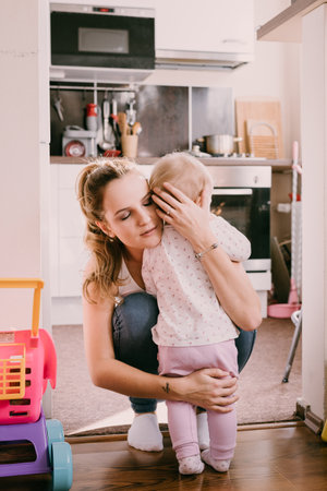 Young mother comforting her toddler child at home, mum and her baby hugging. Family life, everyday parenting. Apartment living, young family. Loving relationship. Care.のeditorial素材