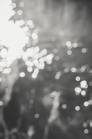 Blur bokeh background of water with flecks of sunlight. Monochrome photoの写真素材