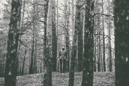 A lonely guy in a pine forest in the autumn time. Monochrome photo.の写真素材