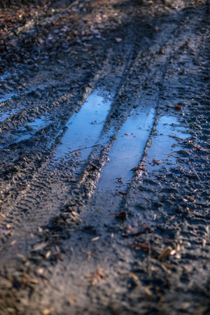Dirty rural road with mud and water in autumn time