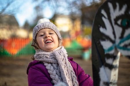 A cute little girl on a playground in autumnの写真素材