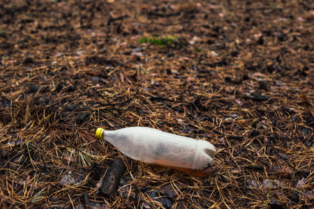 Plastic white bottle on the ground in the pine forest.