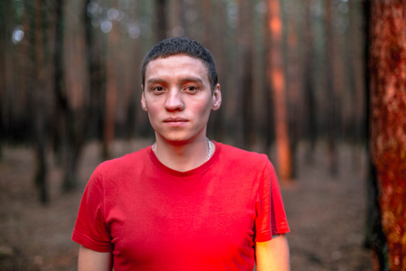 A young guy in a red T-shirt in a pine forestの写真素材