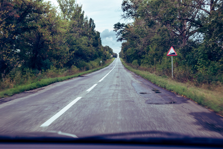 Dark asphalt road in the forest. View from the car.の写真素材