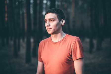 A young guy in a red T-shirt in a pine forestの写真素材