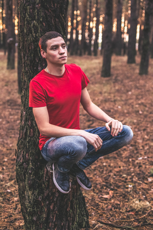 A young guy in a red T-shirt in a pine forestの写真素材