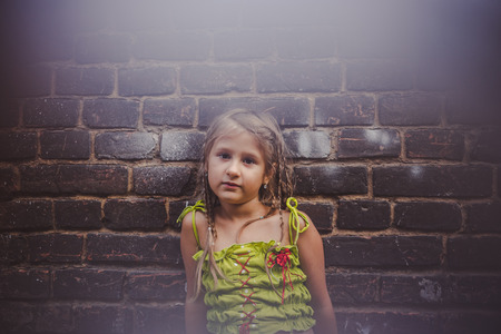 Portrait of a little girl near a brick wallの写真素材