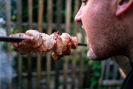 The man eats shish kebab on the skewerの写真素材