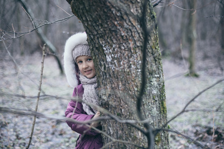 Cute little girl in pine forest in autumn time.の写真素材