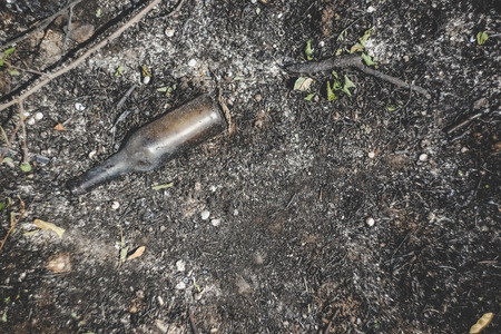 A glass beer bottle lies on the scorched groundの写真素材
