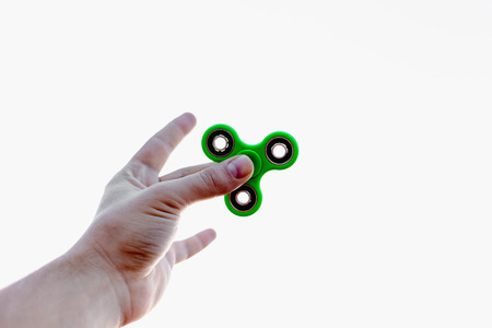 Close up of a man's hand who is holding green fidget spinnerの写真素材