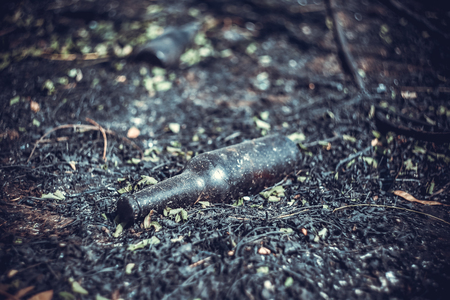 A glass beer bottle lies on the scorched groundの写真素材
