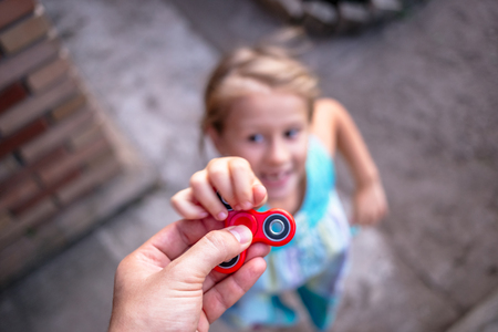 Little girl jumping to the hand with a red spinnerの写真素材