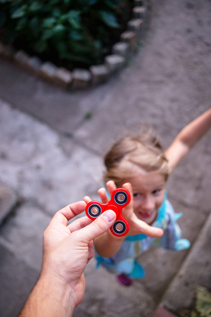 Little girl jumping to the hand with a red spinnerの写真素材