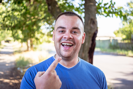 Young man in a blue T-shirt with a chipped toothの写真素材