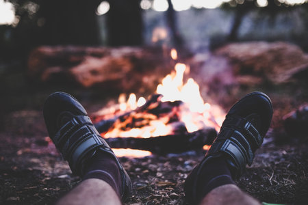 A cyclist resting by the fire in the forest.