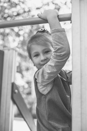 Little cute girl on the playground in the summer. Monochrome old style photo.の写真素材