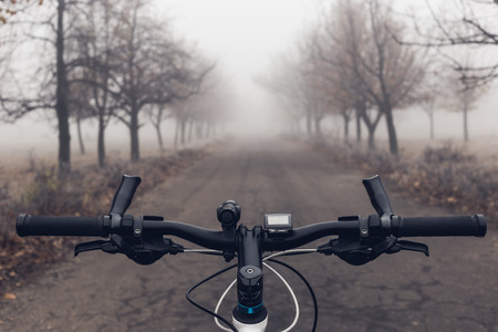 Bicycle and old asphalt road in autumn park with trees in the fog.の写真素材