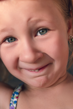 Portrait of a little girl with a wobbly baby tooth.の写真素材