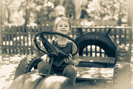 Little cute girl on the playground in the summer. Monochrome old style photo.の写真素材
