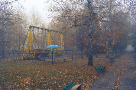 Benches in an old abandoned amusement park on a foggy autumn morning.の写真素材