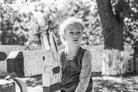 Little cute girl on the playground in the summer. Monochrome old style photo.の写真素材
