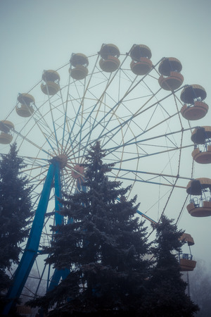 Ferris wheel in an old abandoned park in the autumn in thick fog.の写真素材
