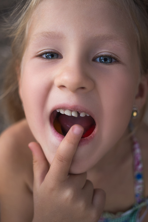 Little girl points the finger at a wobbly baby tooth.の写真素材