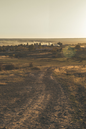 Smoke over the village in the autumn. Burning foliage in Ukraine. The concept of environmental pollution. View from the fields.の写真素材