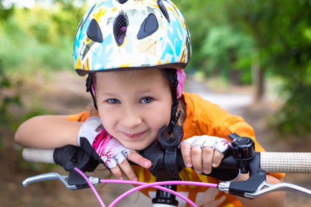 Cute little girl in a helmet with a bike in the summer.の写真素材