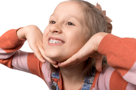 Portrait of little girl with orthodontics appliance isolated on white background.