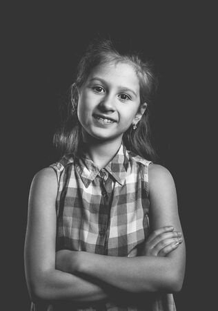 Cute little girl posing on black background. Monochrome style photo.の写真素材